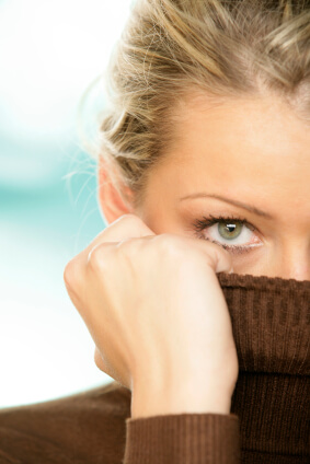 Woman with sensitive skin covering lower face with brown turtleneck sweater, showing perioral dermatitis concern area