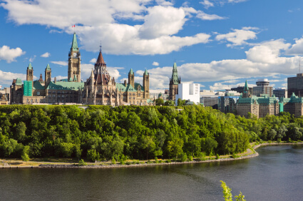 Ottawa Parliament Buildings across Ottawa River with lush green trees showing urban environment impact on skin