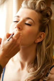 Model applying makeup with soft natural lighting, demonstrating flawless skin preparation for professional beauty look