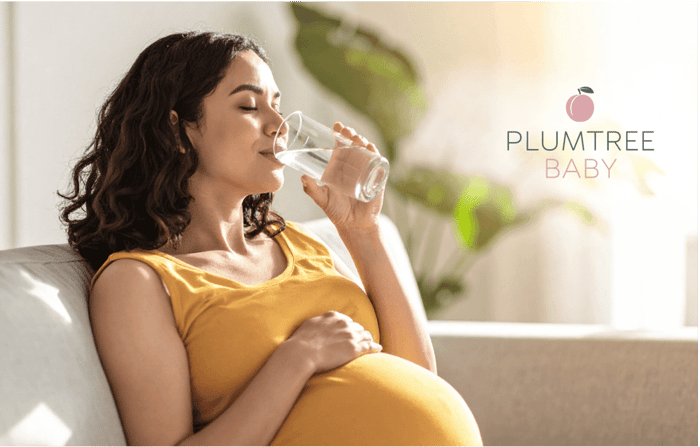 A pregnant woman drinking a glass of water