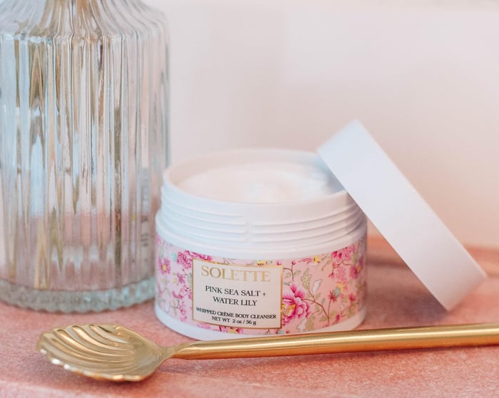 can you use body wash as hand soap? a jar of pink sea salt water lily body wash with a gold spoon and flowers in the background.