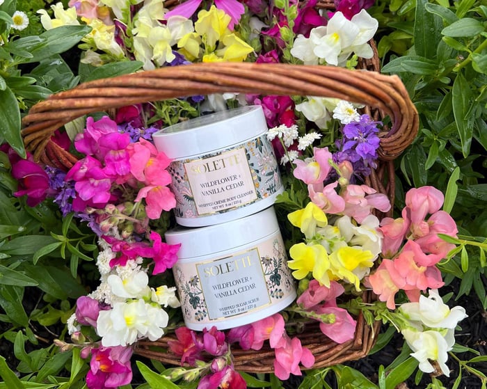 spring body care products in a bed of flowers nestled in a basket