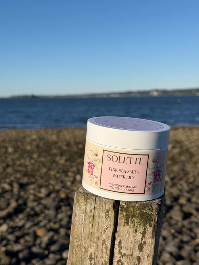 pink sea salt and water lily sugar scrub paired with a pink shaving razor and a white and blue hand towel