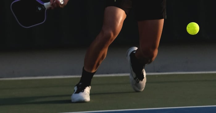 A senior pickleball player swinging one of the best pickleball paddles for seniors on an outdoor court.
