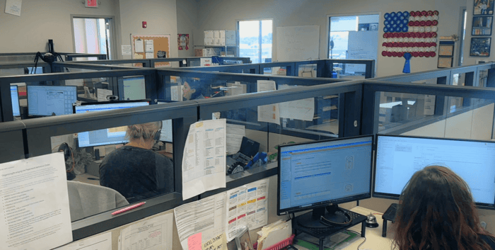 Customer service team members at Hodges Badge Company working at their computers in the office workspace.