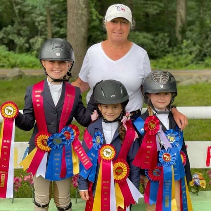 Three young equestrians with their custom Hodges award rosettes that they won at their horse show competition.