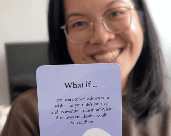 A woman holding up Scenario Cards to the camera to initiate a deep, playful conversation.