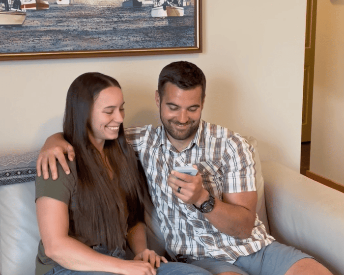 A couple sitting closely together on a couch having a deep conversation and holding space with Scenario Cards.
