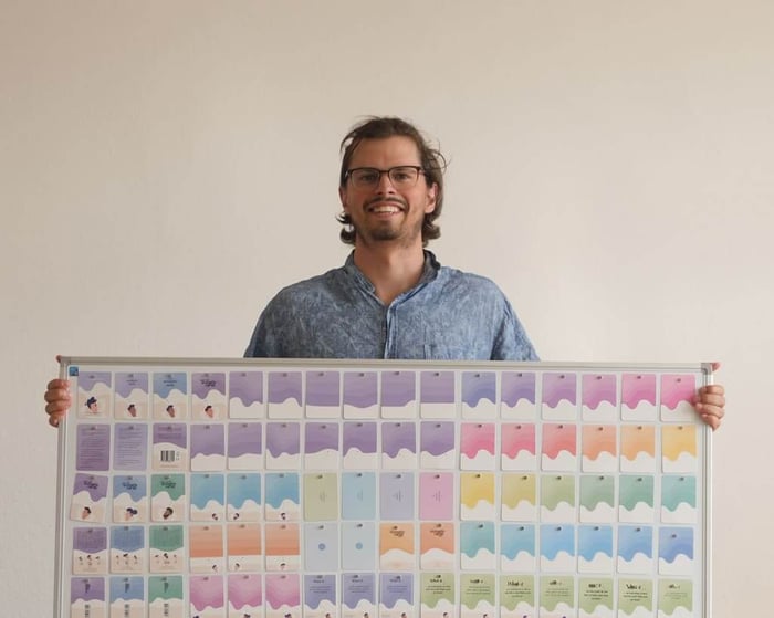 Founder Roel Vogels holding a design board featuring the artwork and layouts for Scenario Cards.