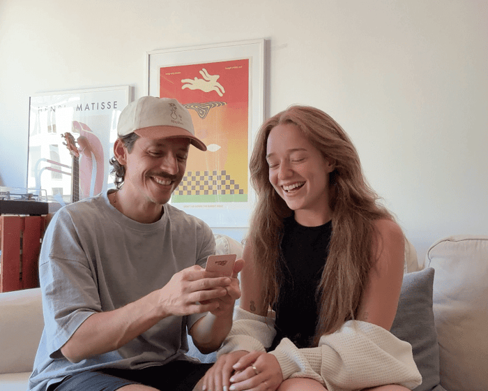 A happy couple on a couch using Scenario Cards to start a deep conversation and bond.