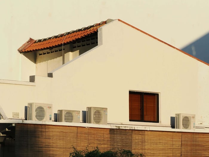 seasonal home maintenance checklist for modern home exterior with multiple AC units