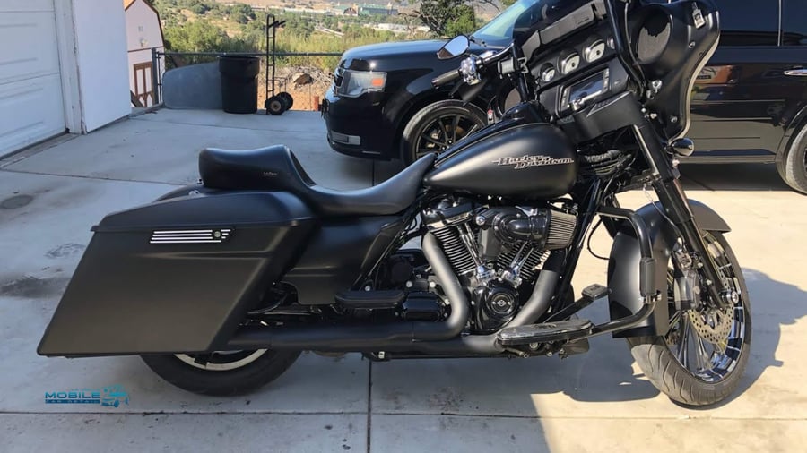 A black harley after professional mobile motorcycle detailing in San Diego, using specialized tools to clean a high-end bike in a driveway.