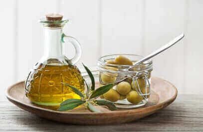 Two teaspoons of golden olive oil demonstrating the daily amount needed for health benefits