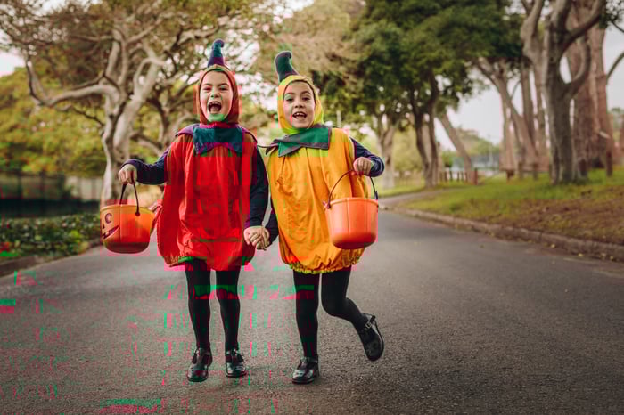 Twin girls dressed like bell peppers skipping down the street while trick-or-treating.  
