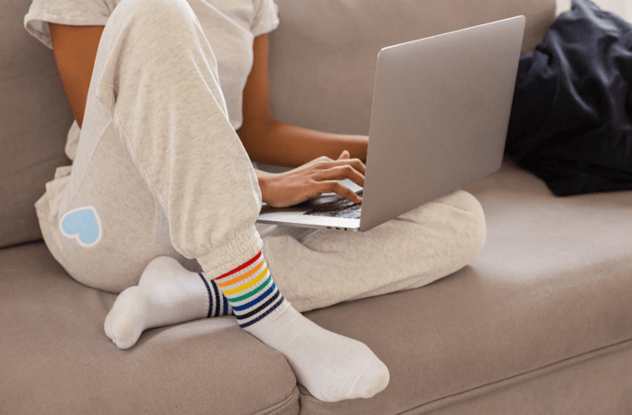 girl sitting on her computer on the couch wearing custom embroidered sweatpants