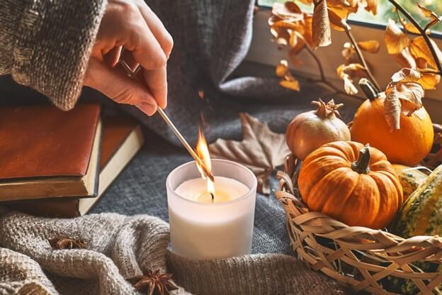 Woman Lighting a Candle on a Table with a Pumpkinscape