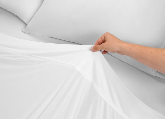 Woman Pulling Over a SHEEX Temperature Regulating Sheet After Reviewing Her Sleep Score