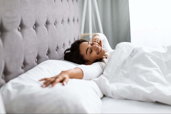 Woman Stretching Out on Her Bed While Putting Her Head on a Lavender Infused Pillow by SHEEX