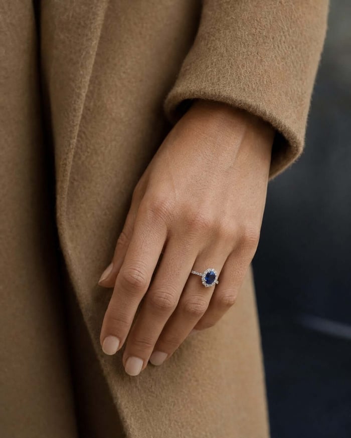 Blue sapphire and natural diamond statement ring beside a camel wool coat cuff