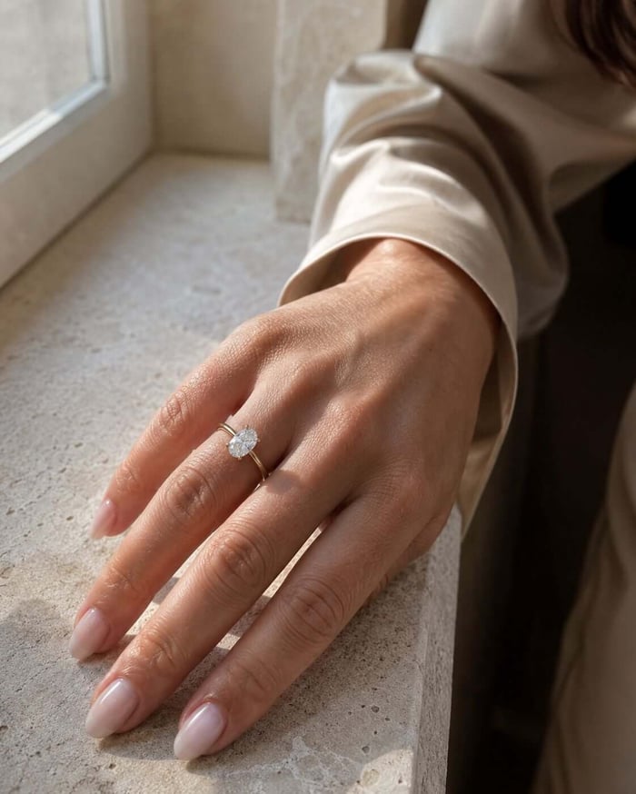 Woman wearing an almost colourless natural diamond ring beside a stone window ledge