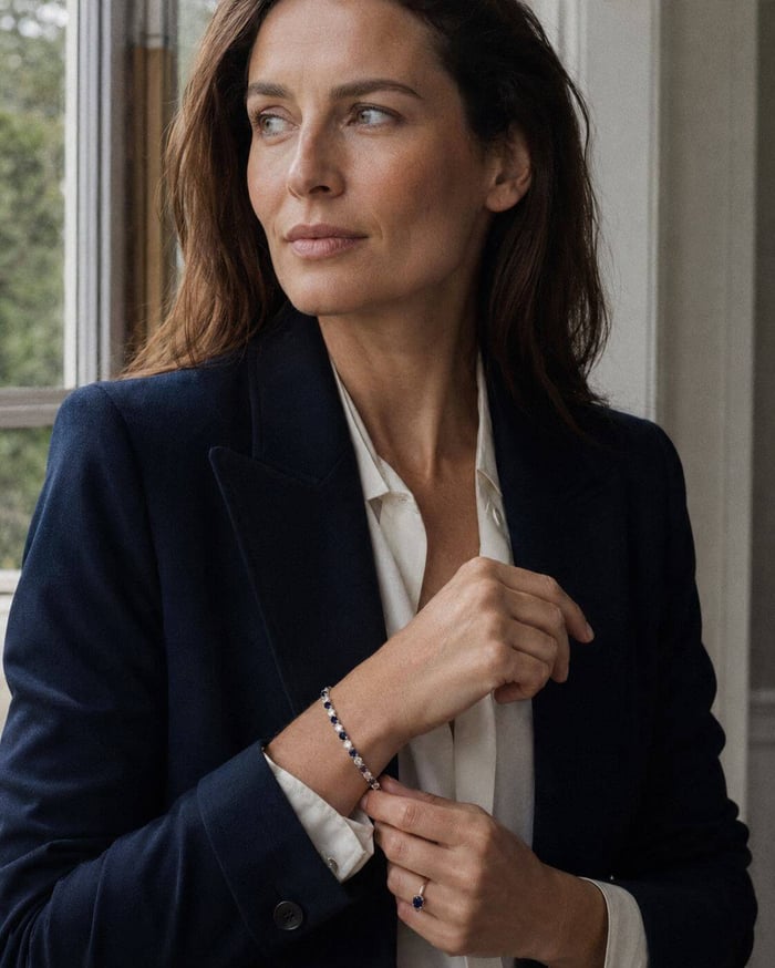 Woman in navy and ivory tailoring wearing a blue sapphire and natural diamond bracelet.