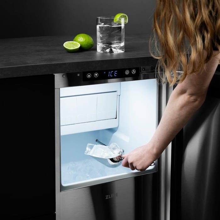 Woman scooping ice out of a ZLINE 15 in. Touchstone Gourmet Ice Maker with Drain Pump and Solid Stainless Steel Door (IGMD-ST-15)