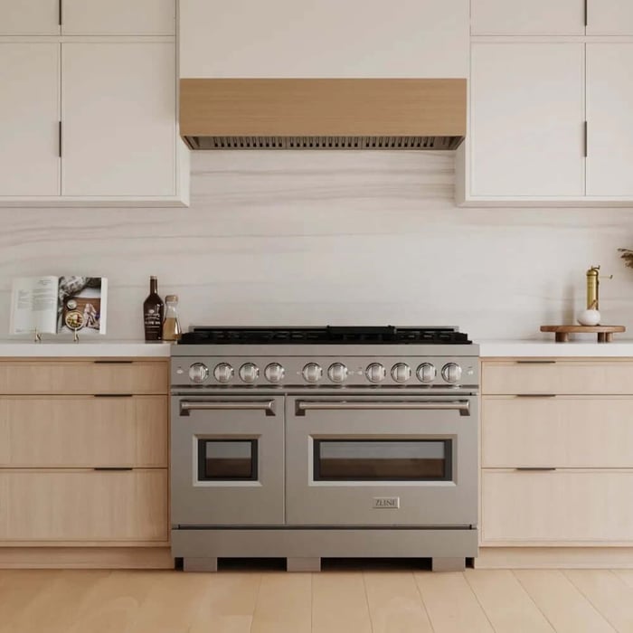 A stainless steel range in a kitchen with light wood details