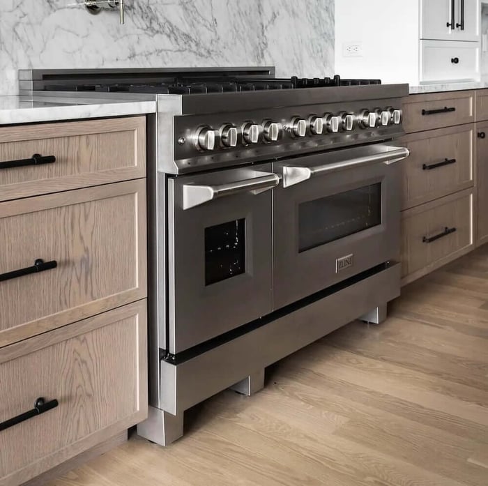 A stainless steel range in a kitchen with wood details and floors