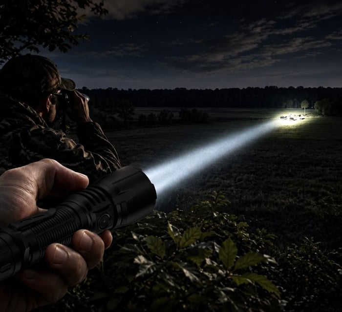 long-throw white hunting flashlight beam scanning an open field at night