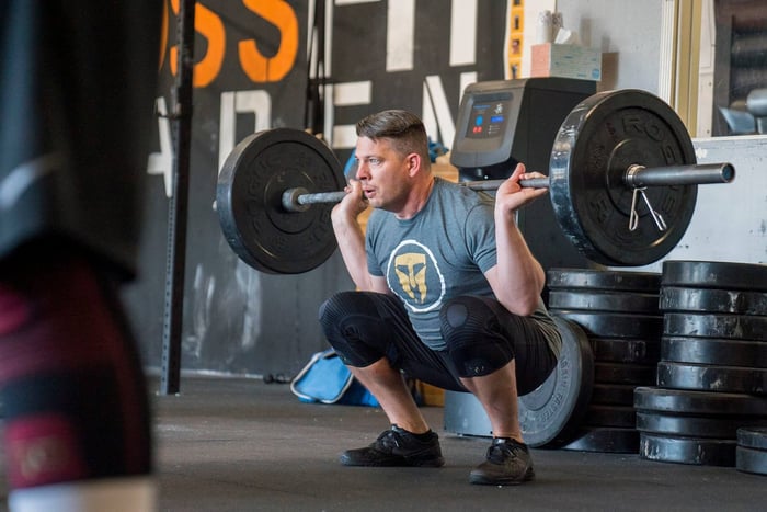 Man weightlifting while wearing GO Sleeves knee sleeves as an alternative to layering knee support.