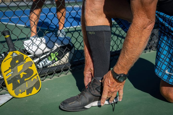 Athlete putting on a GO Sleeves calf sleeve before a pickleball match to help support against a pickleball calf injury.