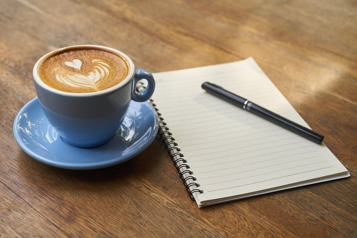 cup of coffee on table with pen and paper