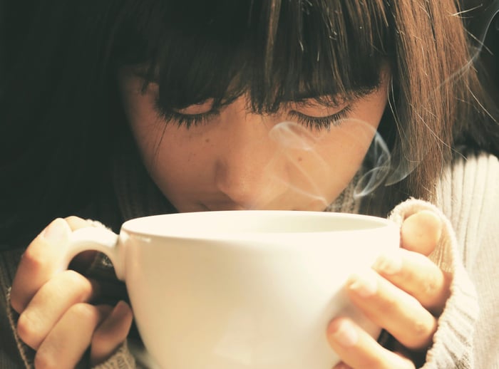 Woman holding white cup