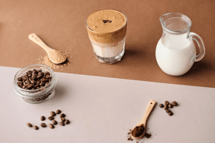 glass of whipped Dalgona coffee with milk, coffee beans, and ingredients