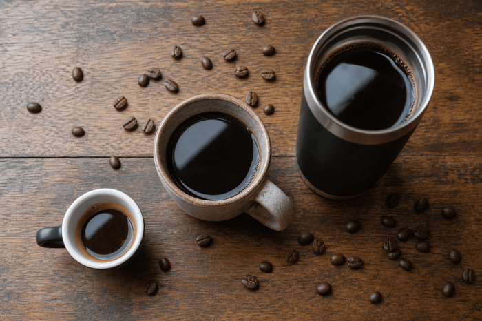 Three cups of coffee with scattered beans on wooden table.