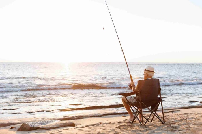 Old man fishing by the beach shore