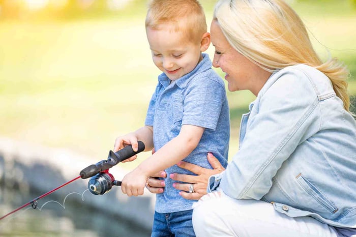 Mother teaching her young son how to fish.