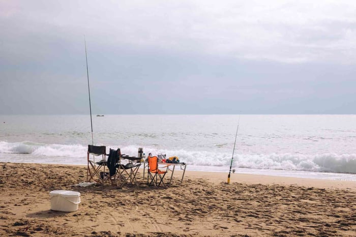 Two chairs with fishing rods by the beach