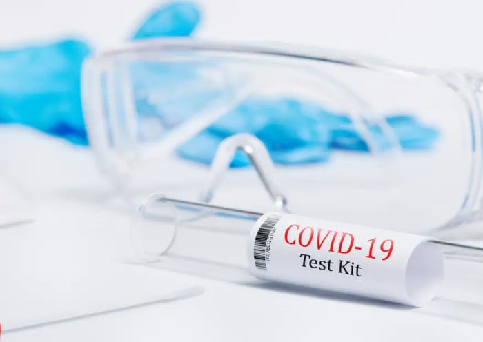 COVID-19 Test Kid mit Schultzbrille und medizinischen Handschuhen im Hintergrund