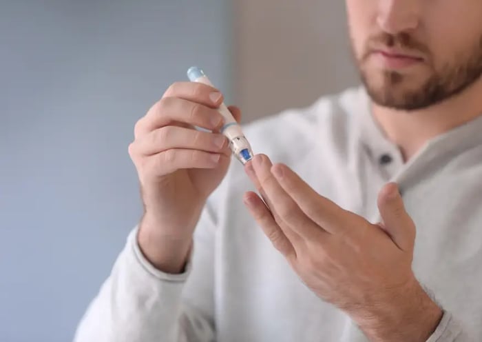 Mann stichtt sich in seinen Finger, um seinen Blutzucker zu messen