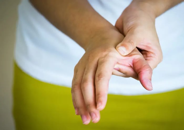 Eine Hand übt Druck auf die andere Hand zwischen Daumen und Zeigefinger aus