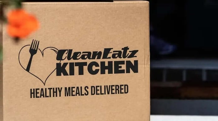 Affordable premade meal delivery boxes and plated Clean Eatz Kitchen meals displayed with branded packaging and ready-to-eat dishes