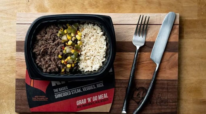 Balanced prepared meal portions tray with shredded steak, mixed vegetables, and rice on cutting board beside fork and knife.
