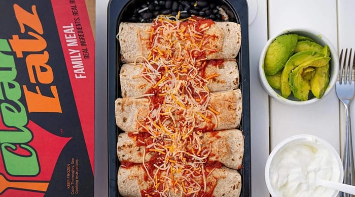 Balanced prepared meal portions featuring enchiladas with black beans, topped with sauce and shredded cheese, served with avocado and sour cream.