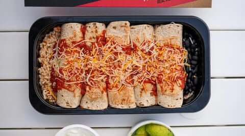 Frozen meal plan delivery featuring enchiladas with rice and beans in portion-controlled black container.