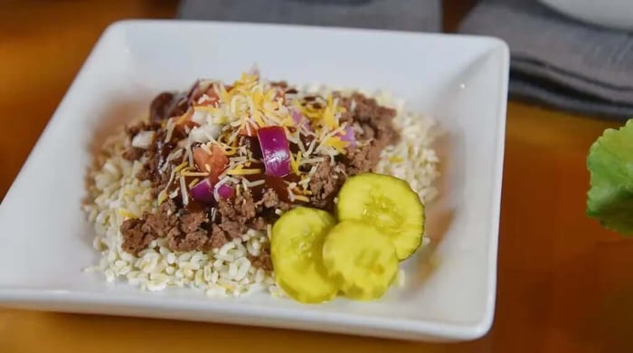 Gluten-free prepared meals served on a plate with ground beef, rice, cheese, onions, and pickle slices.
