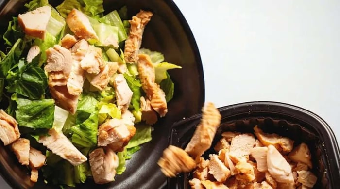 Healthy eating plans featuring grilled chicken salad with fresh lettuce in a meal prep bowl.