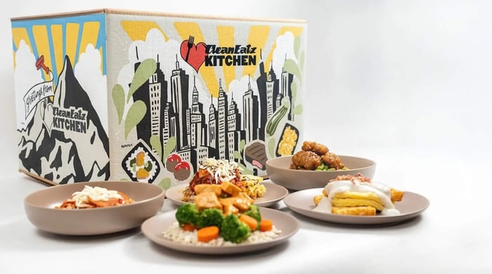 healthy low-calorie meal delivery featuring assorted Clean Eatz Kitchen meals plated beside a branded catering box