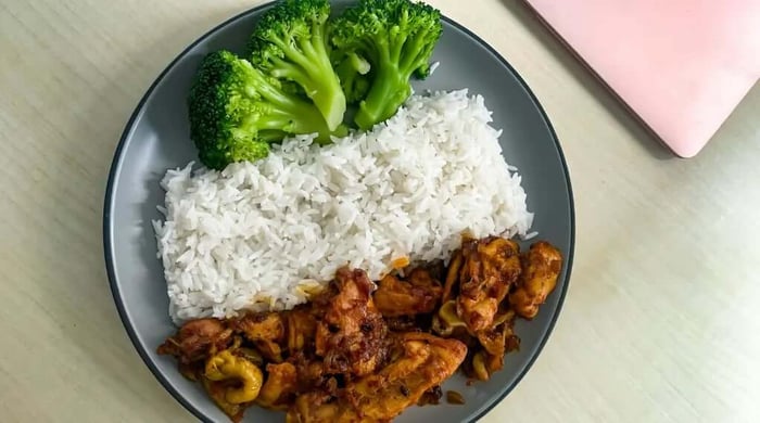 Macro-friendly meal of saucy chicken, white rice, and steamed broccoli served on a grey plate.