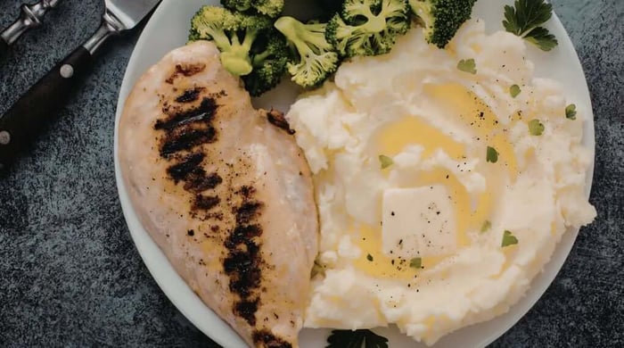 High protein meals featuring a grilled chicken breast with buttery mashed potatoes and steamed broccoli on a white plate.